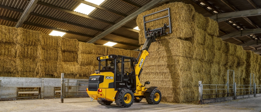 TM110 lifting bales in a shed 